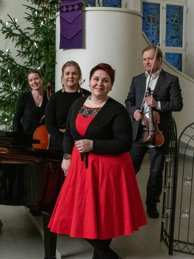 Kuvassa etualalla on nainen punaisessa hameessa, taustalla mustiin pukeutuneita ihmisiä.