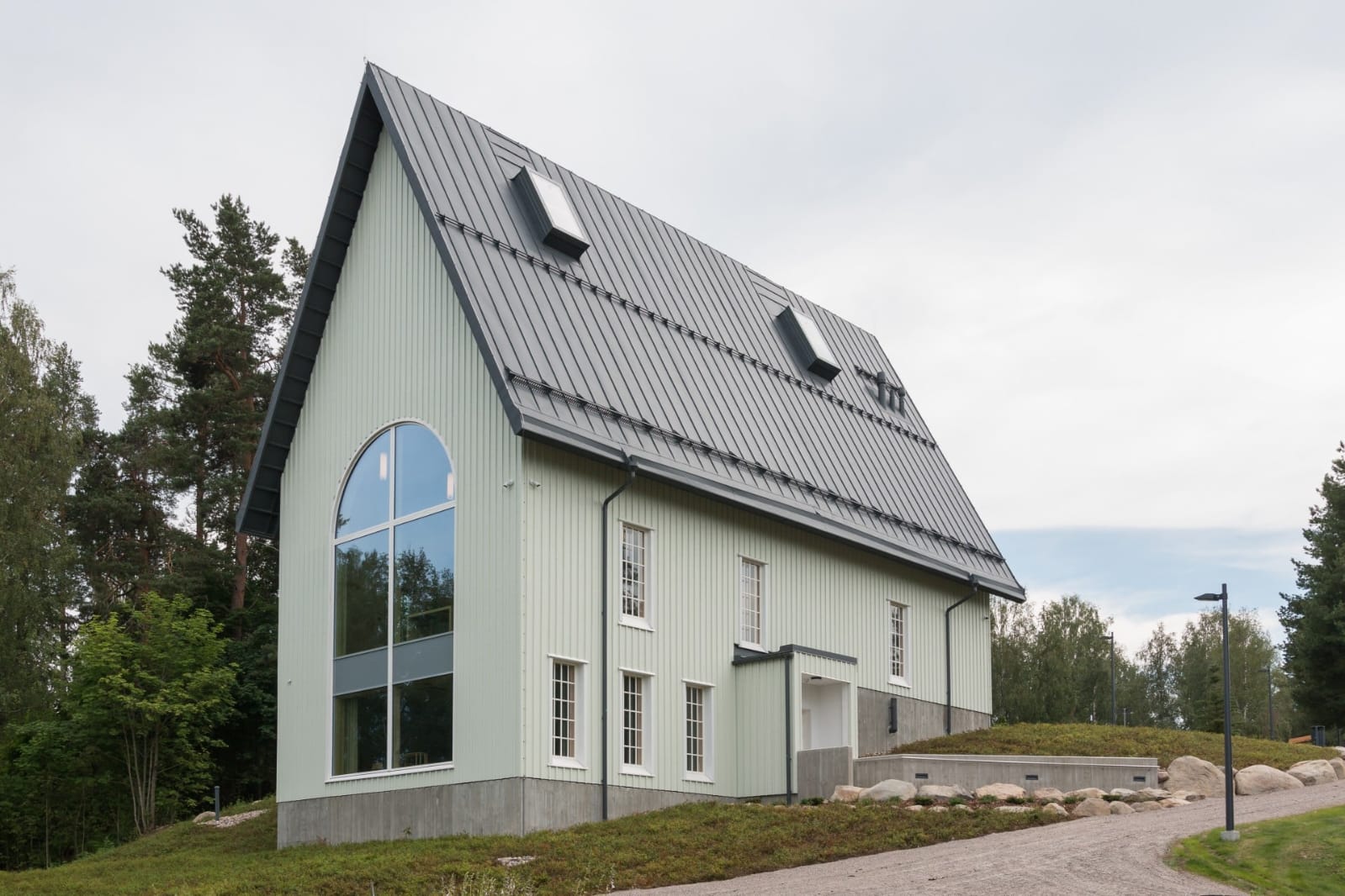 Kuva Rautjärven kirkosta ulkoa päin. Vihreä kirkko. Hautausmaan metsä taustalla.